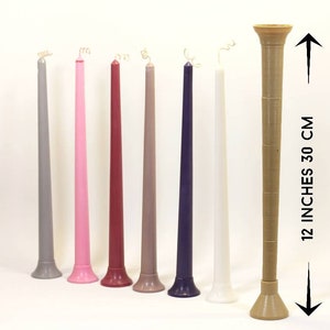 May include: Seven taper candles in various colors, including gray, pink, red, brown, purple, and white, with a gold wick. The candles are 12 inches tall and have a diameter of about 1 inch. The candles are arranged in a row on a white surface.