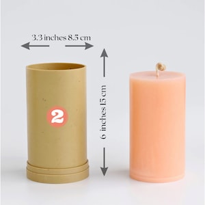 May include: A beige candle mold with a 2 printed on it, next to a peach-colored candle with a wick. The mold is 6 inches tall and 3.3 inches wide. The candle is 6 inches tall and 3.3 inches wide.