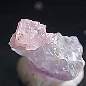 May include: A cluster of pink and purple amethyst crystals with a rough, natural texture. The crystals are translucent and have a slight shimmer.
