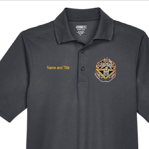 May include: Dark gray polo shirt with a collar and short sleeves. The shirt features a logo on the right chest and the text "Name and Title" above the chest. The right sleeve has the text "BOR" and "DR".