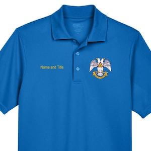 May include: A short-sleeved, royal blue polo shirt. The shirt features a collar, three buttons, and an embroidered emblem on the chest. The emblem includes a double-headed eagle and the text "Name and Title" in yellow.