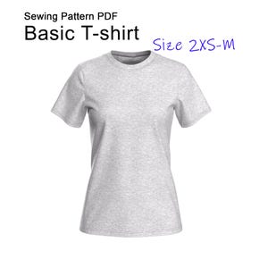 May include: A light gray basic T-shirt with short sleeves. The shirt has a crew neck and is made of a soft, textured fabric. Text on the image reads "Sewing Pattern PDF Basic T-shirt Size 2XS-M".