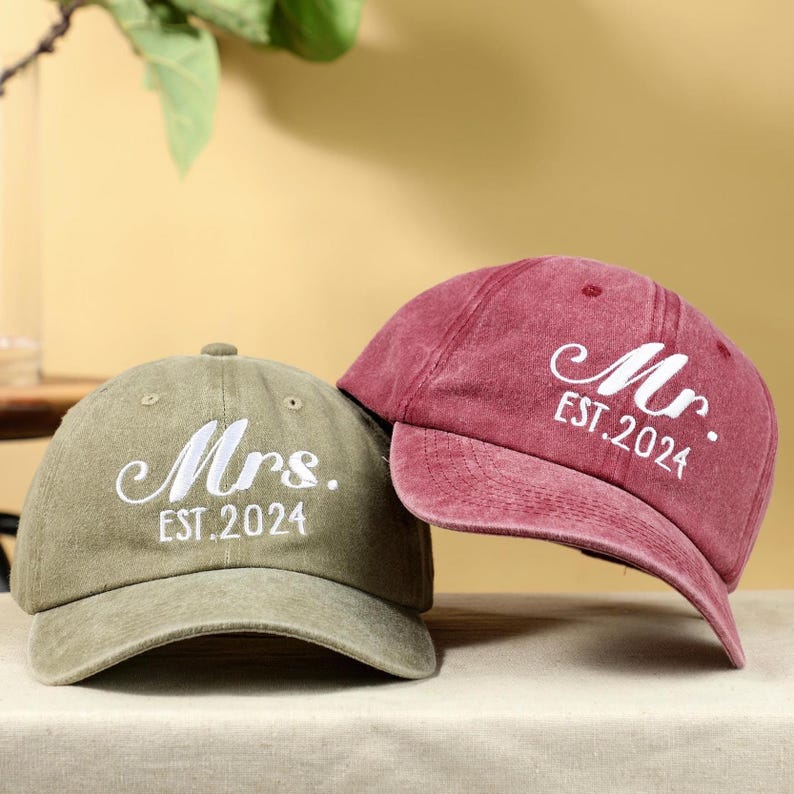 May include: Two baseball caps, one green and one burgundy, with the words "Mrs. EST. 2024" and "Mr. EST. 2024" embroidered in white.