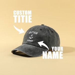 May include: A black denim baseball cap with an embroidered anchor and the text "Captain Herman". The text "YOUR NAME" is written below the cap.