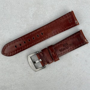 May include: Two brown leather watch straps with stitching. One strap has a silver buckle and the text "Watch & Strap" embossed on it.