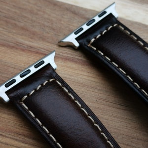 Top of the Berlin brown leather apple watch strap fitted with 316L stainless steel apple watch connectors. Placed on a wood background under natural lighting.