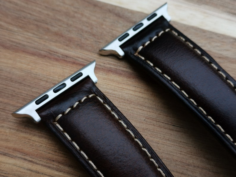 Top of the Berlin brown leather apple watch strap fitted with 316L stainless steel apple watch connectors. Placed on a wood background under natural lighting.