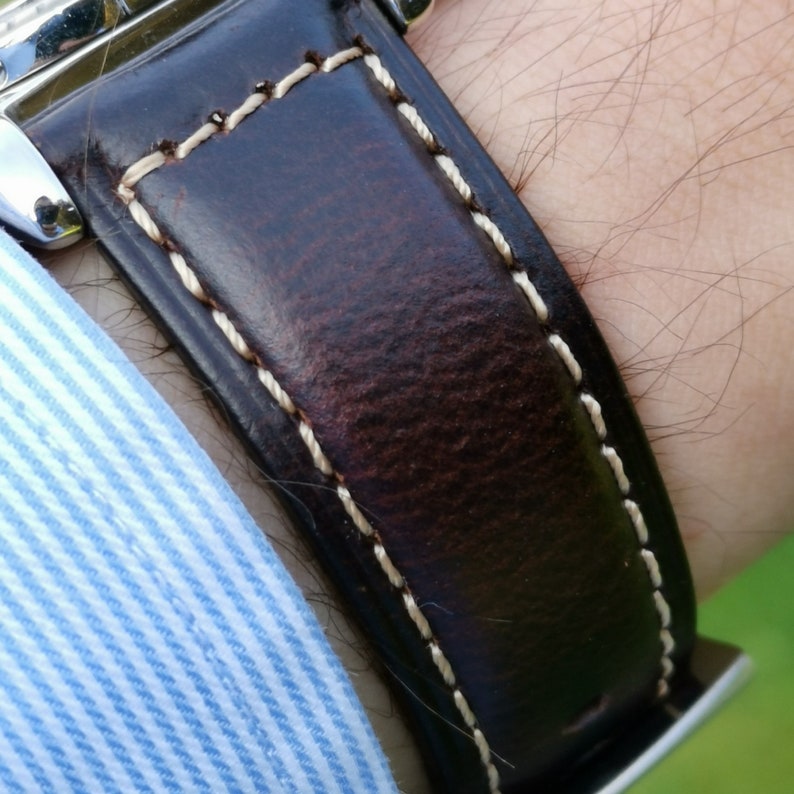 Wrist shot of the Berlin brown leather apple watch strap. Brown leather apple watch band. Close up shot showing the cracked brown leather and contrast light gold stitching.