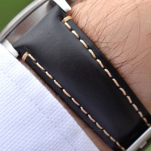 Wrist shot of the Oslo black full grain leather watch band. Picture clearly shows the grain of the leather and the contrast ivory stitching. Picture taken on a males wrist.