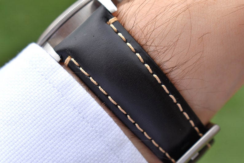 Wrist shot of the Oslo black full grain leather watch band. Picture clearly shows the grain of the leather and the contrast ivory stitching. Picture taken on a males wrist.