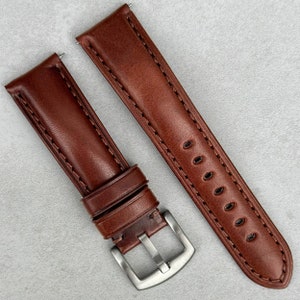 May include: Two brown leather watch straps with stitching. One strap has a silver buckle and the other has a silver keeper.