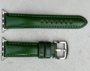 May include: A green leather watch band with silver-colored hardware. The band is made of a smooth, solid green leather and features a buckle closure. The band is designed to fit a smartwatch.
