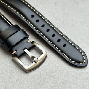 Brushed 316L stainless steel buckle on the Oslo black full grain leather watch strap. Placed on a grey background under natural lighting.