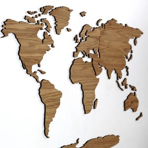 May include: A wooden world map wall art piece, showcasing the continents in a detailed, cut-out design. The map is made of light brown wood and mounted on a white wall. The continents are clearly defined, offering a decorative and educational element.