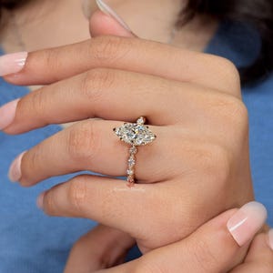 May include: A gold ring featuring a large marquise-cut center stone surrounded by smaller round and marquise-cut stones along the band. The metal has a warm, polished finish, and the design includes a delicate setting that highlights the stones.