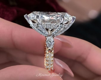 May include: A ring featuring a large elongated marquise-cut center stone set in silver-toned metal with a hidden halo of small round stones. The band is gold-toned and encrusted with multiple rows of small round stones, with a marquise-cut side stone.