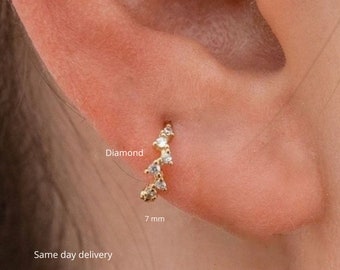 Könnte beinhalten: Ein goldener Creolenohrring mit einer Reihe kleiner Diamanten, die in einer geschwungenen Linie eingefasst sind. Der Ohrring hat einen Durchmesser von 7 mm. Diamant.
