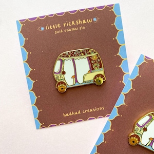 Puede incluir: Pin de esmalte dorado de un rickshaw colorido y decorado con el texto "little rickshaw" y "hudhud creations".