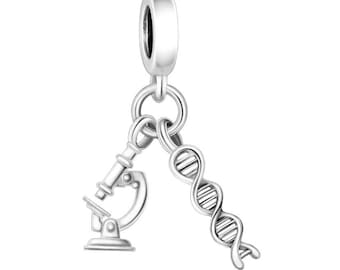 May include: A silver charm featuring a microscope and a DNA strand. The charm has a loop at the top for attaching to a bracelet or necklace. The microscope is detailed, and the DNA strand is a double helix.