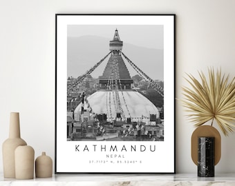 May include: Monochrome framed print of the Boudhanath Stupa in Kathmandu, Nepal. The print includes the text "KATHMANDU NEPAL" and coordinates 27.7172° N, 85.3240° E. The print is displayed with decorative vases and a dried plant.