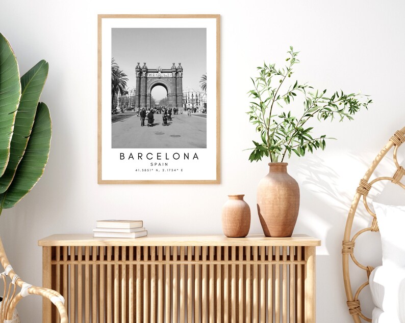 May include: Black and white photograph of an archway in Barcelona, Spain. The text "BARCELONA" is printed below the image, along with "SPAIN" and the coordinates "41.3851&deg; N, 2.1734&deg; E".
