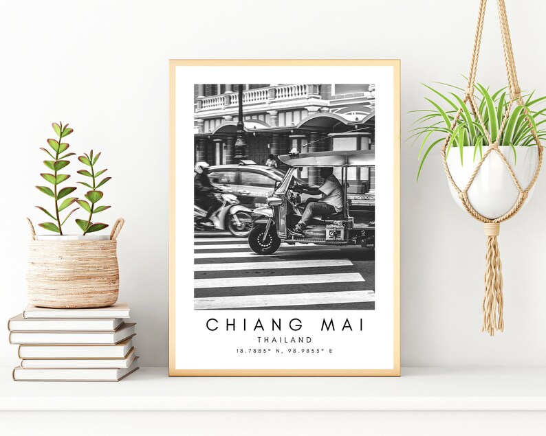 May include: Black and white photograph of a tuk-tuk driving down a street in Chiang Mai, Thailand. The text "CHIANG MAI THAILAND 18.7853&deg; N, 98.9953&deg; E" is printed below the image.