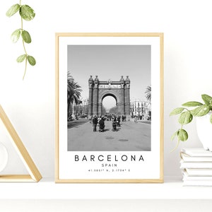 May include: Black and white photograph of the Arc de Triomf in Barcelona, Spain. The archway is made of stone and has a large arch in the center. There are people walking in front of the archway. The text "BARCELONA, SPAIN, 41.3851&deg; N, 2.1754&deg; E" is printed below the image.