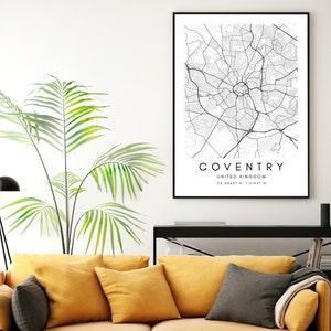 May include: Black and white map print of Coventry, United Kingdom. The map shows the city's streets and landmarks. The print is framed and hanging on a white wall.