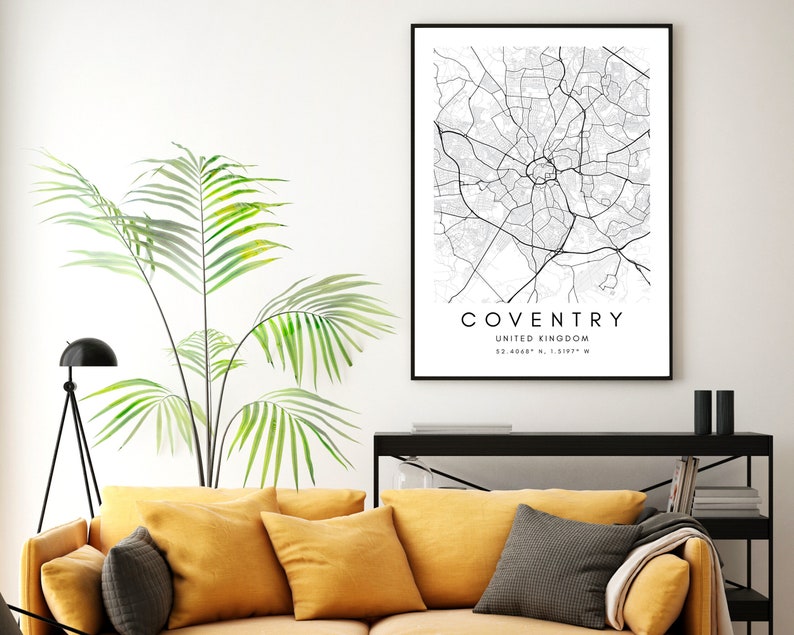 May include: Black and white map print of Coventry, United Kingdom. The map shows the city's streets and landmarks. The print is framed and hanging on a white wall.