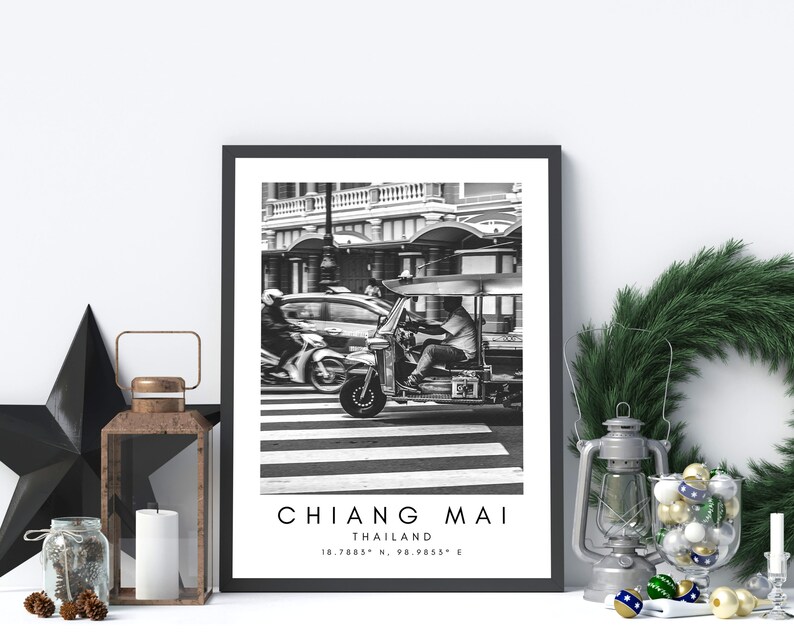 May include: Black and white photograph of a tuk-tuk driving through a crosswalk in Chiang Mai, Thailand. The text "CHIANG MAI, THAILAND, 18.7885&deg; N, 98.9855&deg; E" is printed below the image.