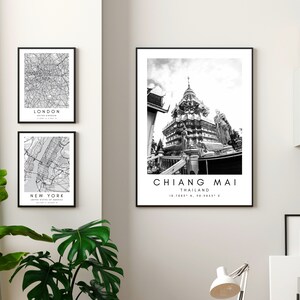 K&ouml;nnte beinhalten: Drei Schwarzwei&szlig;-Bilder in schwarzen Rahmen an einer wei&szlig;en Wand. Das obere Bild zeigt ein Schwarzwei&szlig;foto eines Tempels in Chiang Mai, Thailand. Unter dem Foto steht der Text "CHIANG MAI" und "THAILAND". Das mittlere Bild zeigt eine Schwarzwei&szlig;karte von New York City. Das untere Bild zeigt eine Schwarzwei&szlig;karte von London.