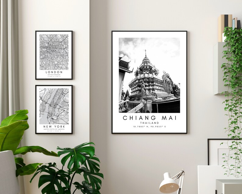 K&ouml;nnte beinhalten: Drei Schwarzwei&szlig;-Bilder in schwarzen Rahmen an einer wei&szlig;en Wand. Das obere Bild zeigt ein Schwarzwei&szlig;foto eines Tempels in Chiang Mai, Thailand. Unter dem Foto steht der Text "CHIANG MAI" und "THAILAND". Das mittlere Bild zeigt eine Schwarzwei&szlig;karte von New York City. Das untere Bild zeigt eine Schwarzwei&szlig;karte von London.