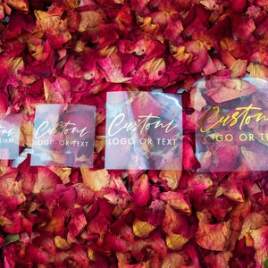 May include: Four clear plastic stickers with the text "Custom Logo or Text" in gold and white lettering on a background of red rose petals.