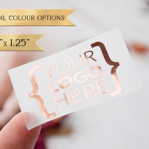 May include: A 2.0" x 1.25" clear sticker with a rose gold foil design. The sticker says "YOUR LOGO HERE" inside of curly brackets.