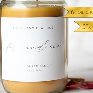 May include: A clear glass jar candle with a white label that reads "Americano Classics" and "fire and ice" in cursive script. The label also says "Oured Candle" and "0 oz | 285g". The candle is a light amber colour. The image also includes two gold ribbon banners with the text "8 Foil Choices" and "3" x 2.5".
