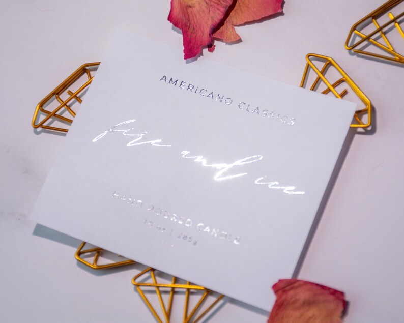 May include: A white card with silver foil lettering that reads "American Classics" and "fire and ice". The card is sitting on a white surface with gold diamond-shaped clips.