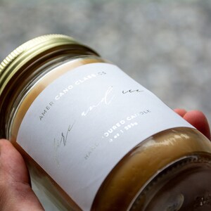 May include: A white candle jar with a gold lid. The label reads "Americano Classics" and "Fire and Ice" in silver lettering. The label also says "Hand-poured candle" and "oz | 283g".