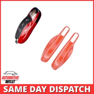 Peut inclure: Une coque de clé de voiture rouge brillant avec un panneau de boutons noir et des icônes blanches, accompagnée de deux poignées en plastique rouge assorties. La clé présente un design lisse et incurvé avec une finition métallique.