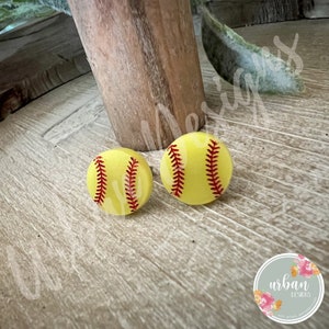 Peut inclure: Une paire de boucles d'oreilles en forme de balle de softball jaunes avec des coutures rouges. Les boucles d'oreilles sont en argile polym&egrave;re et mesurent environ 2,5 cm de diam&egrave;tre.