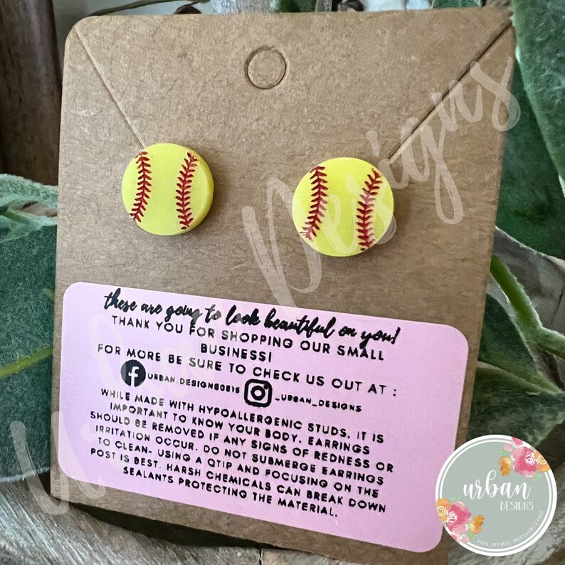 Peut inclure: Une paire de boucles d'oreilles en forme de balle de softball hypoallerg&eacute;niques. Les boucles d'oreilles sont en argile polym&egrave;re et pr&eacute;sentent une balle de softball jaune avec des coutures rouges. Les boucles d'oreilles sont pr&eacute;sent&eacute;es sur une carte brune avec un message rose qui dit "these are going to look beautiful on you! Thank you for shopping our small business! For more be sure to check us out at: [Facebook icon] URBAN_DESIGNBOBIS [Instagram icon] URBAN_DESIGNS While made with hypoallergenic studs, it is important to know your body. Earrings should be removed if any signs of redness or irritation occur. Do not submerge earrings to clean - using a cotton bud and focusing on the post is best. Harsh chemicals can break down sealants protecting the material."