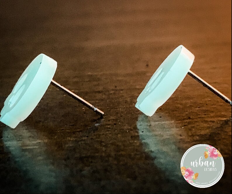May include: A pair of light blue skull stud earrings. The earrings are made of a smooth, opaque material and have a simple, minimalist design.