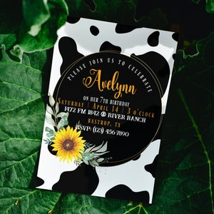 May include: A birthday party invitation with a cow print background. The invitation features a black circle with gold text that reads "Please join us to celebrate Avelynn." A sunflower and greenery are on the bottom left. The invitation is for a 7th birthday.