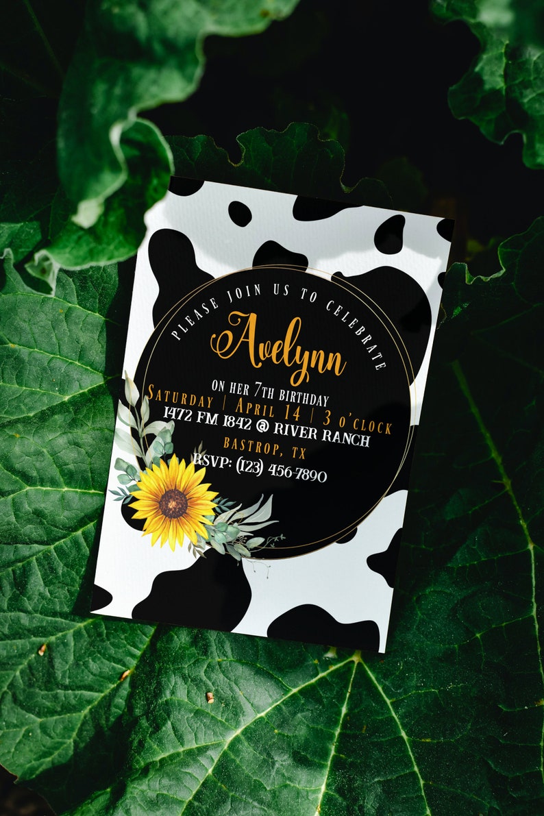 May include: A birthday party invitation with a cow print background. The invitation features a black circle with gold text that reads "Please join us to celebrate Avelynn." A sunflower and greenery are on the bottom left. The invitation is for a 7th birthday.