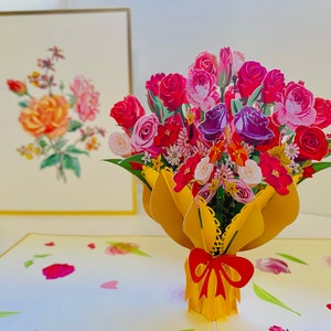 May include: A 3D pop-up card featuring a bouquet of colorful roses, lilies, and other flowers in a yellow vase with a red bow. The card is open and the flowers are standing up.