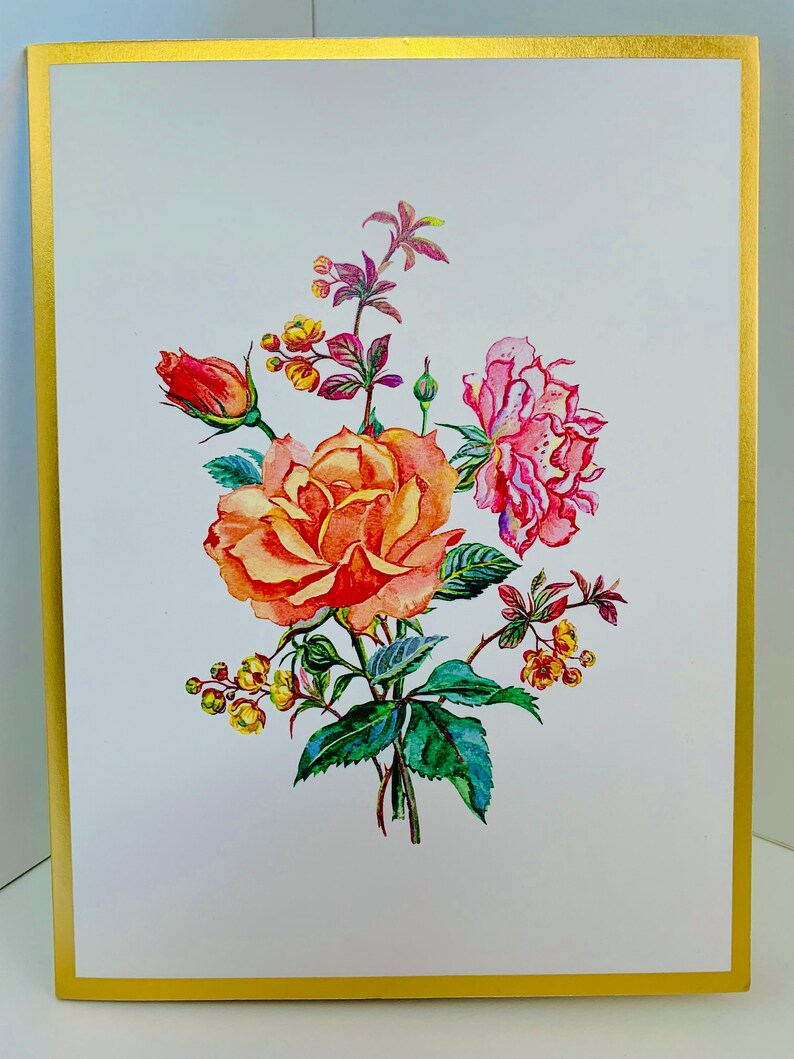 May include: A white card with a gold border features a watercolor painting of a bouquet of flowers. The bouquet includes a large orange rose, a smaller pink rose, and several small yellow flowers. The flowers are arranged in a loose, natural style.