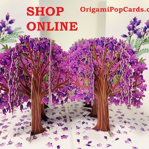 May include: A 3D pop-up card featuring a purple flowering tree. The card is open and the tree is in full bloom. The card is made by OrigamiPopCards.com and the text "SHOP ONLINE" is printed on the front of the card.