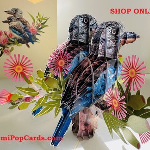 Puede incluir: Una tarjeta pop-up 3D con dos pájaros azules y negros con flores rosas y hojas verdes. La tarjeta está titulada "OrigamiPopCards.com" y tiene el texto "SHOP ONLINE" en letras rojas.