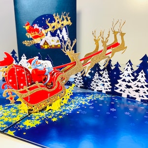 Tarjeta de felicitación navideña 3D desplegable premium con trineo mágico de Papá Noel y renos voladores. Hecha a mano. Tienda online: https://origamipopcards.com/
