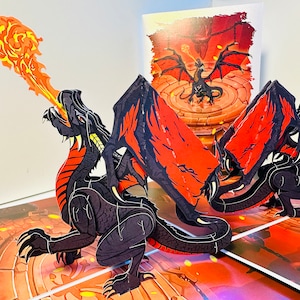 May include: A pop-up card featuring three black dragons with red wings and fiery breath. The dragons are positioned on a detailed, illustrated background with a matching dragon image in the background. The card is designed with intricate cut-out details.