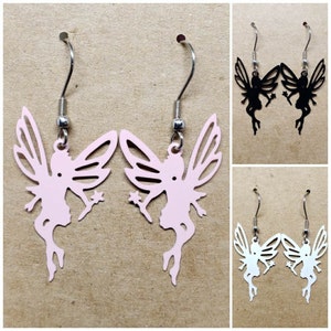 May include: A pair of dangle earrings featuring a fairy silhouette design. The earrings are available in pink, black, and white.